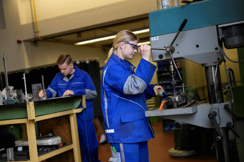Zwei Auszubildende an einer Maschine in einer Werkstatt