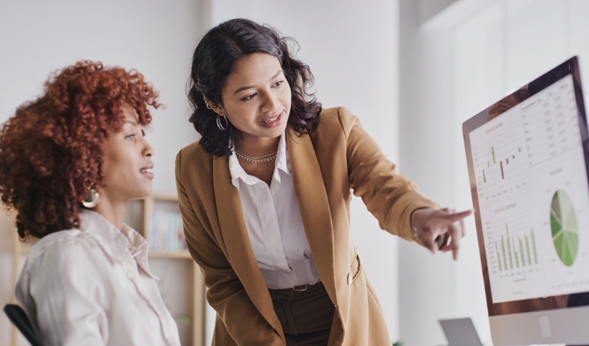 Zwei Frauen vor Bildschirm mit Energieverbrauchsgrafik