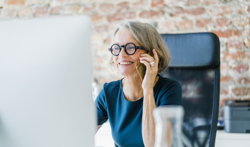 Telefonierende Frau vor Computer Bildschirm