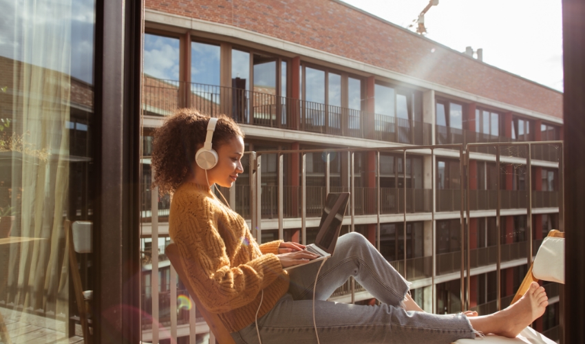 Frau mit Laptop auf Balkon